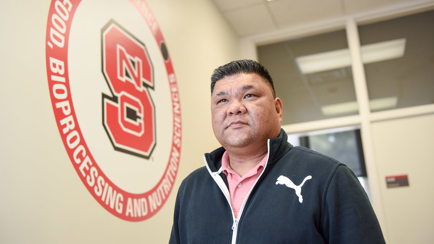 FBNS' Fred Jimenez stands in front of the NC State seal.