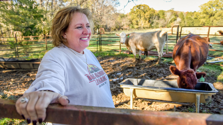 Alamance County's Lisa Glosson, smiling, in the paddock with two of her cattle.