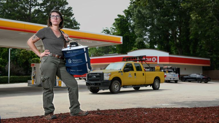 CALS Ph.D. candidate Emily Reed stands boldly in front of a gas station, giant mosquito trap on one hip, gazing into the future.