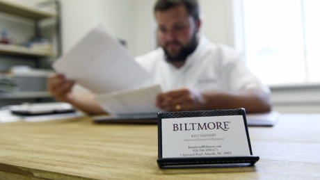 A Biltmore business card in the foreground as Kyle Mayberry works in the background.