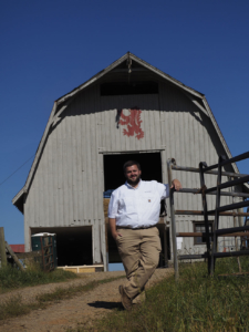 Kyle Mayberry stands in front of a historic barn.