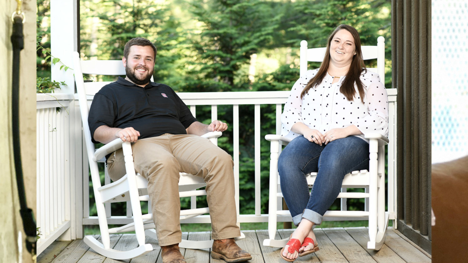 Kyle and Sara Mayberry sit and smile on their front porch.